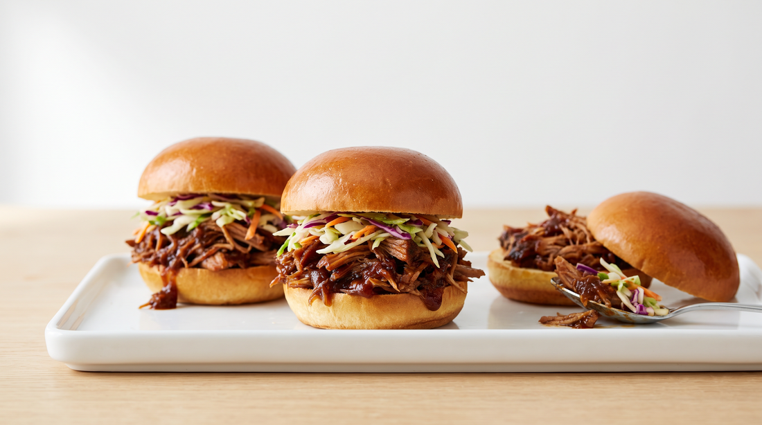 Three pulled pork sliders with slaw on a white plate