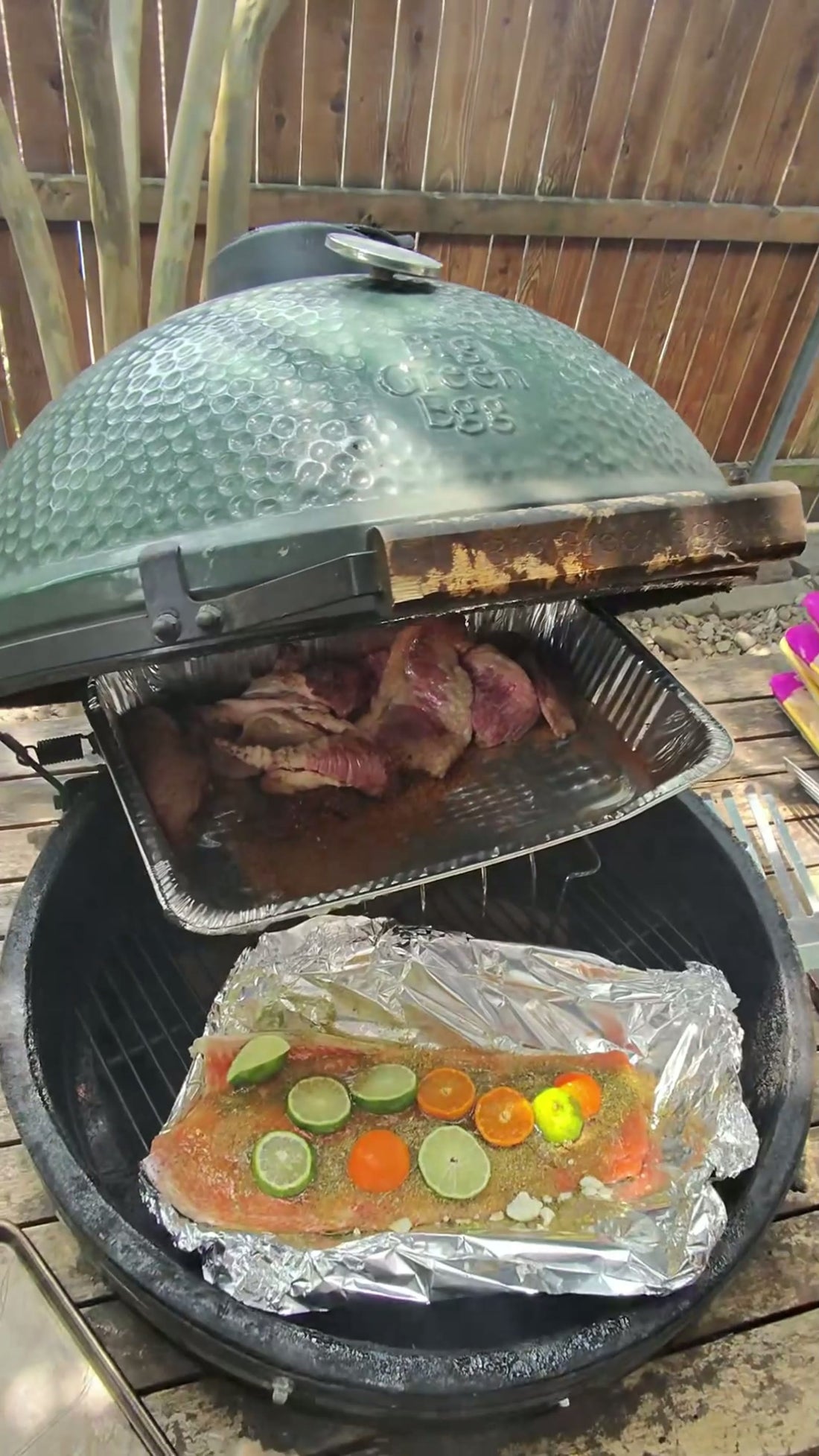 A foil pan of vegetables cooking on a ceramic grill