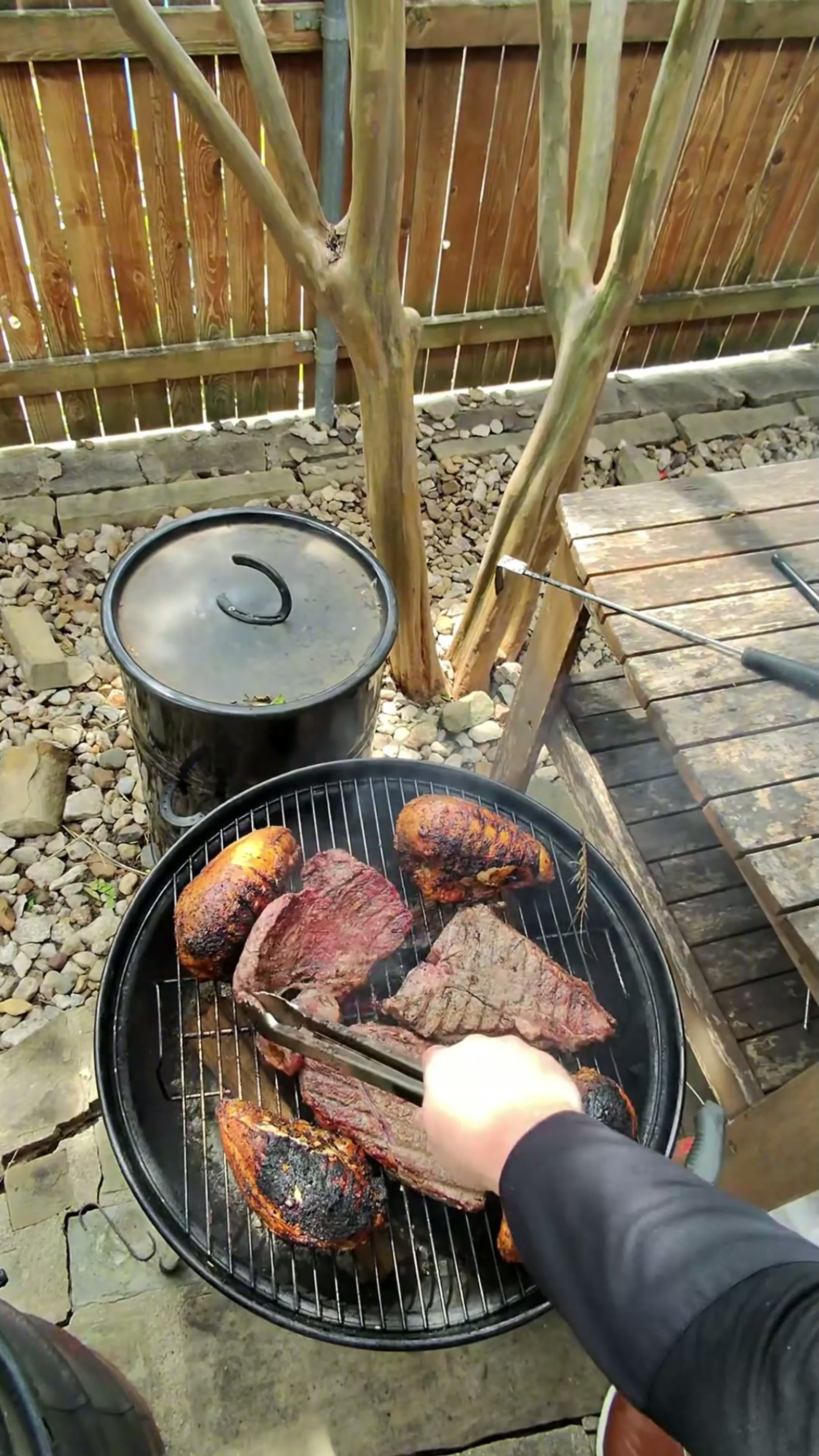 Grilled meat pieces being turned with tongs over charcoal