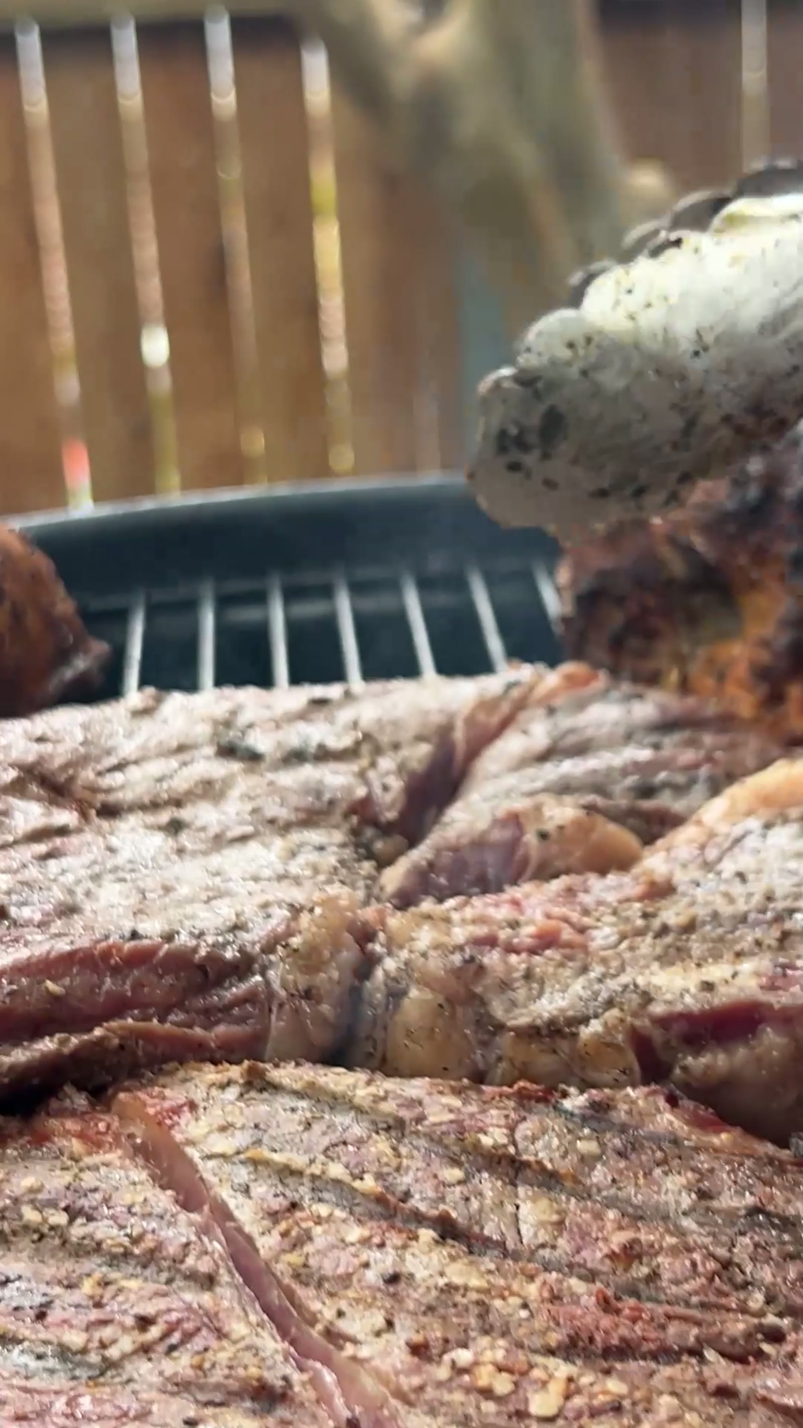 A charred brisket resting on a grill grate